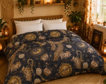 Op de afbeelding: Een donkerblauw dekbed met een herhalend hemels patroon van gouden zonnen met gezichten, maansikkels, sterren en sterrenbeelden. De stof toont gedetailleerde illustraties van astrologische kaarten en sterrenbeelden in goud- en crèmetinten.