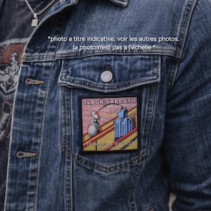 Peut inclure: Veste en jean bleue avec un patch Black Sabbath sur la poche poitrine. Le patch affiche le nom du groupe et le titre de l'album "Technical Ecstasy" avec un graphisme coloré. La veste a une fermeture boutonnée et un col.