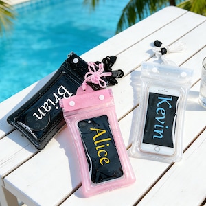 May include: Three waterproof phone cases in black, pink, and clear, each with a phone inside. The black case has the name "Brian" in white, the pink case has "Alice" in yellow, and the clear case has "Kevin" in blue. All cases have a lanyard.