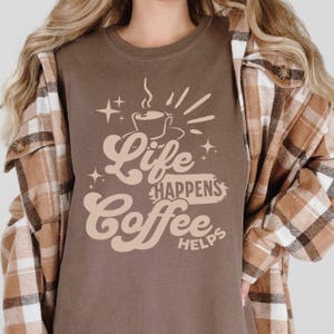 Peut inclure: Une tasse en céramique blanche avec une anse noire et le texte "But First, Coffee" en gras noir. La tasse est posée sur un fond flou. La tasse mesure environ 10 cm de hauteur.