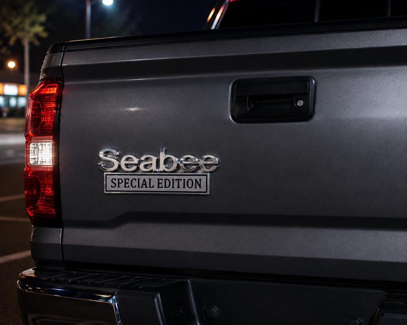 Pu&ograve; includere: Primo piano del portellone posteriore grigio di un pick-up. L'emblema cromato recita "Seabee Special Edition". Il fanale posteriore &egrave; rosso con una luce di retromarcia bianca. Lo sfondo &egrave; scuro, suggerendo la notte.