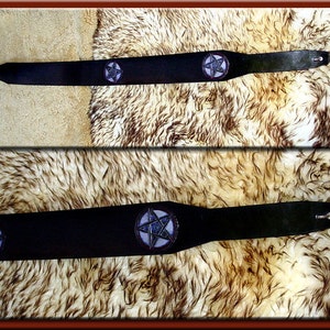 May include: Black leather guitar strap with a pentagram design in purple and blue.