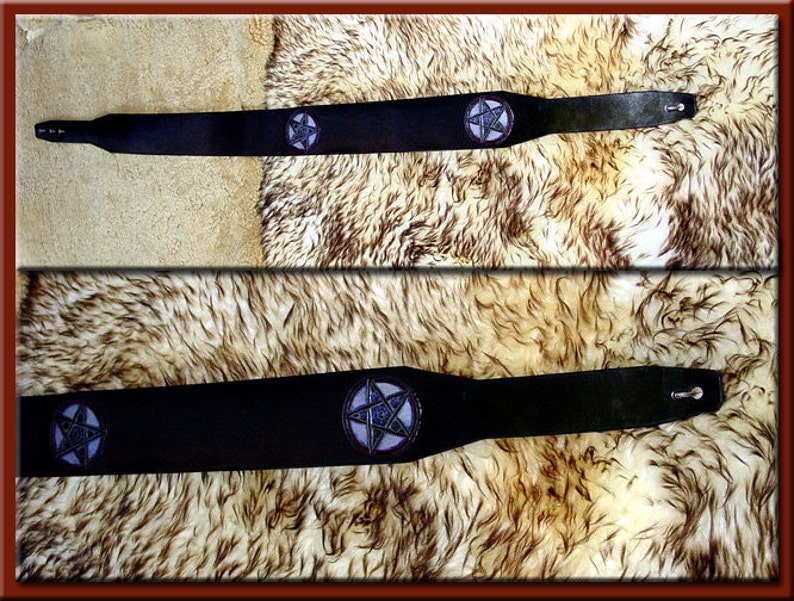 May include: Black leather guitar strap with a pentagram design in purple and blue.