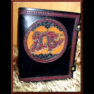 May include: Black leather journal with a red and black stitched border. The cover features a circular design with a red dragon embossed in the center.