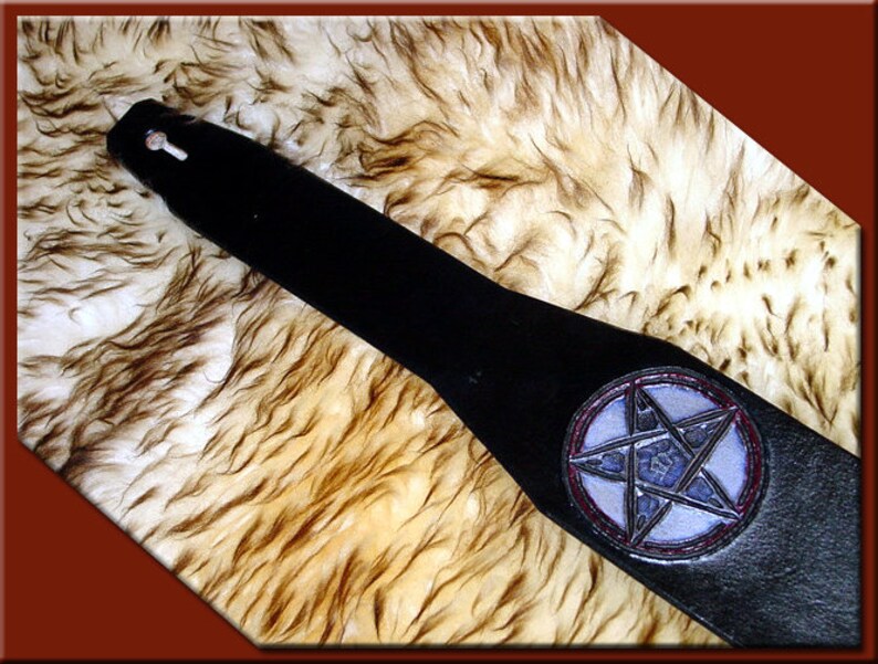 May include: Black leather guitar strap with a silver pentagram design in a red circle.