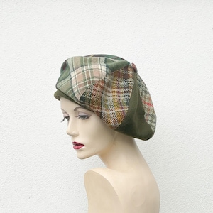 Könnte beinhalten: Eine grüne, braune und beige karierte Baskenmütze mit grünem Samtbesatz. Die Baskenmütze wird auf dem Kopf einer Schaufensterpuppe getragen.