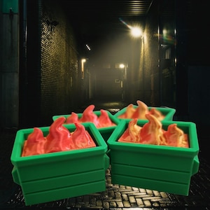 May include: Several green rectangular containers with red and orange flame-shaped objects inside. The containers are arranged in a group, with a dark alleyway in the background.