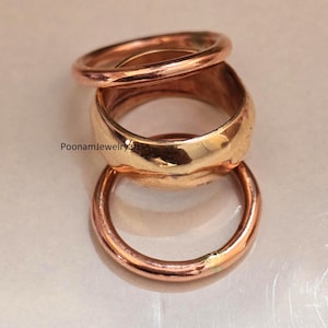 Peut inclure: Un empilement de trois bagues en cuivre poli avec une finition lisse et arrondie. L'anneau central est plus large que les deux bandes plus fines positionnées au-dessus et en dessous. Le texte PoonamJewelryArts est visible sur l'anneau central.