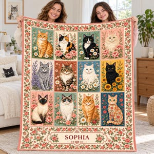 May include: A rectangular throw blanket featuring a grid of twelve illustrated cats surrounded by various flowers. The blanket has a floral border and the name SOPHIA printed in a central rectangular frame at the bottom of the design.
