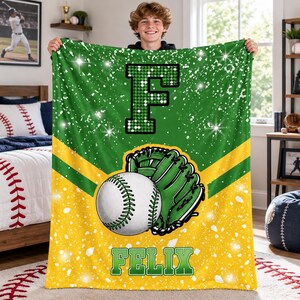May include: A soft fleece blanket featuring a green and yellow gradient background with white speckles. The design includes a large letter F, a white baseball, a green baseball glove, and the name FELIX printed in green block letters.