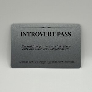 May include: A gray card with rounded corners, featuring the text "INTROVERT PASS" in bold black letters. Below, smaller text reads "Excused from parties, small talk, phone calls, and other social obligations, etc."