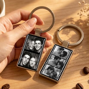 May include: Two rectangular metal keychains featuring a black and white film strip design. Each keychain displays multiple candid photographs of couples in a vertical sequence. The keychains have a silver-toned metal frame and a circular split ring.