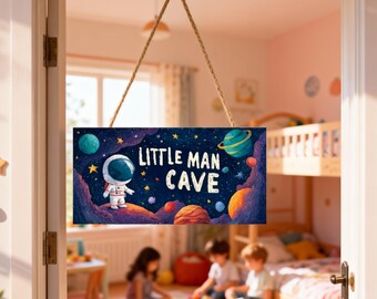 May include: A rectangular wooden sign with the text "LITTLE MAN CAVE" and an illustration of an astronaut in a space scene. The sign is suspended by a natural rope and hangs in a doorway.