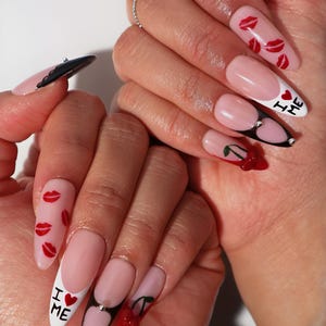 May include: Long, almond-shaped acrylic nails with a pink base and white tips. Designs include red lips, cherries, and the text "I ❤️ ME". Some nails have black accents and rhinestones.