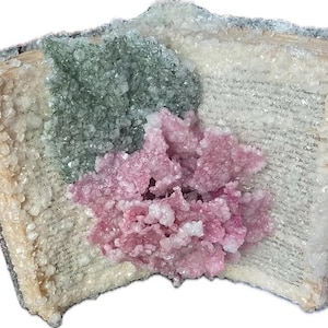 May include: An open book with pages visible, encrusted with crystals. The crystals are in shades of white, green, and pink, creating a textured, decorative piece. The book's edges are also covered in crystals.