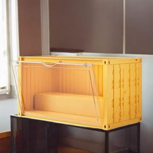 Peut inclure: Un conteneur de stockage jaune avec une porte transparente à charnière. Le conteneur est rectangulaire et repose sur un support en métal noir. La porte est partiellement ouverte, révélant l'intérieur.
