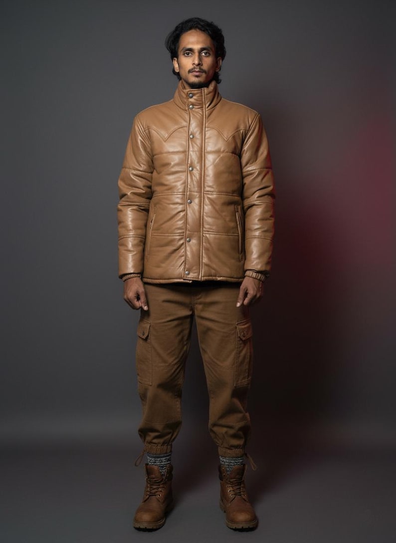 K&ouml;nnte beinhalten: Hellbraune Lederjacke mit Knopfleiste und hohem Kragen, kombiniert mit passender Cargohose und braunen Stiefeln. Das Outfit ist ein komplettes Set, perfekt f&uuml;r einen robusten, Outdoor-Look. Die Jacke hat ein gestepptes Design.