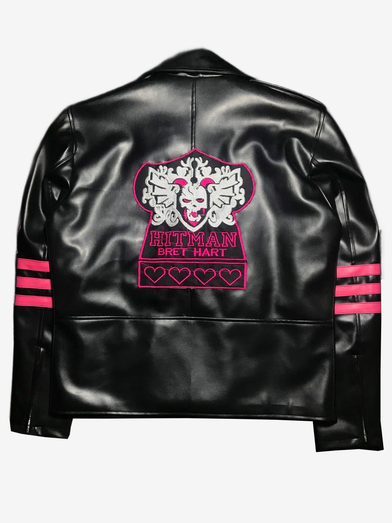 May include: Black leather jacket with pink accents. Features a pink and white embroidered design on the back with the text "HITMAN BRET HART". Includes pink stripes on the sleeves and four pink heart outlines.
