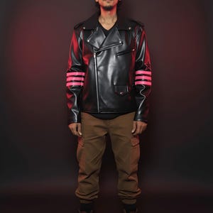 May include: Black leather jacket with a notched collar, asymmetrical zipper, and pink striped accents on the sleeves. The jacket is paired with brown cargo pants and brown boots. The background is a dark red.