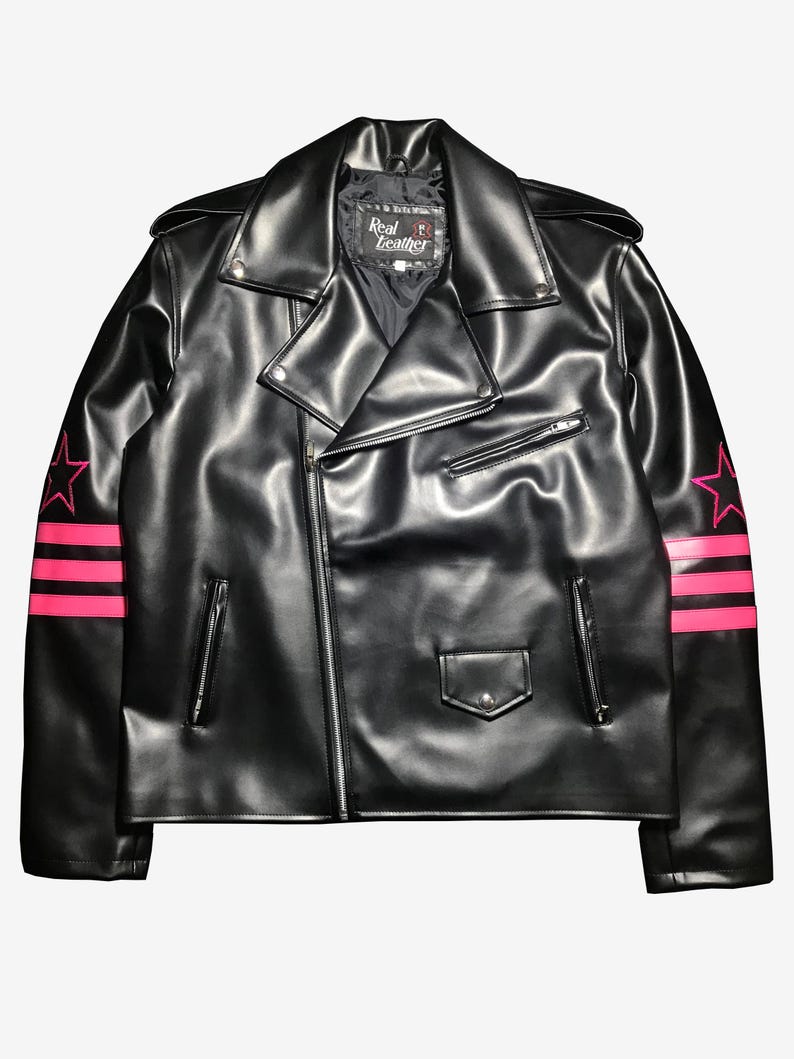 May include: Black leather jacket with a classic biker style, featuring a notched collar, asymmetrical zip closure, and multiple pockets. The sleeves are adorned with pink star and stripe designs. The label reads "Real Leather".