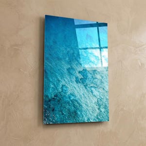 Puede incluir: Una pieza de arte mural rectangular con un dise&ntilde;o vibrante con tem&aacute;tica oce&aacute;nica. La obra de arte presenta tonos de azul y turquesa, creando una apariencia texturizada similar al agua. La superficie brillante refleja la luz, realzando la profundidad visual.