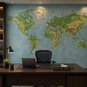 Peut inclure: Un bureau avec une grande carte du monde murale aux terres vertes et océans bleus. Un bureau en bois sombre porte un ordinateur portable, une lampe noire, une petite plante en pot et un panneau indiquant FOCUS - PLAN - ACHIEVE. Une chaise noire est devant.