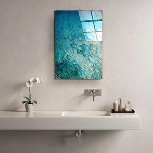 Puede incluir: Una pieza de arte mural rectangular con un dise&ntilde;o abstracto texturizado, turquesa y azul, cuelga sobre un lavabo blanco. Tambi&eacute;n se ven una peque&ntilde;a orqu&iacute;dea en maceta y art&iacute;culos de tocador.