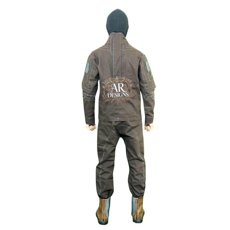 May include: A brown jumpsuit with a hood and boots. The back of the jumpsuit features the text "AR DESIGNS" in a decorative font. The outfit has light-coloured stitching and patches on the sleeves. The boots are brown and blue.