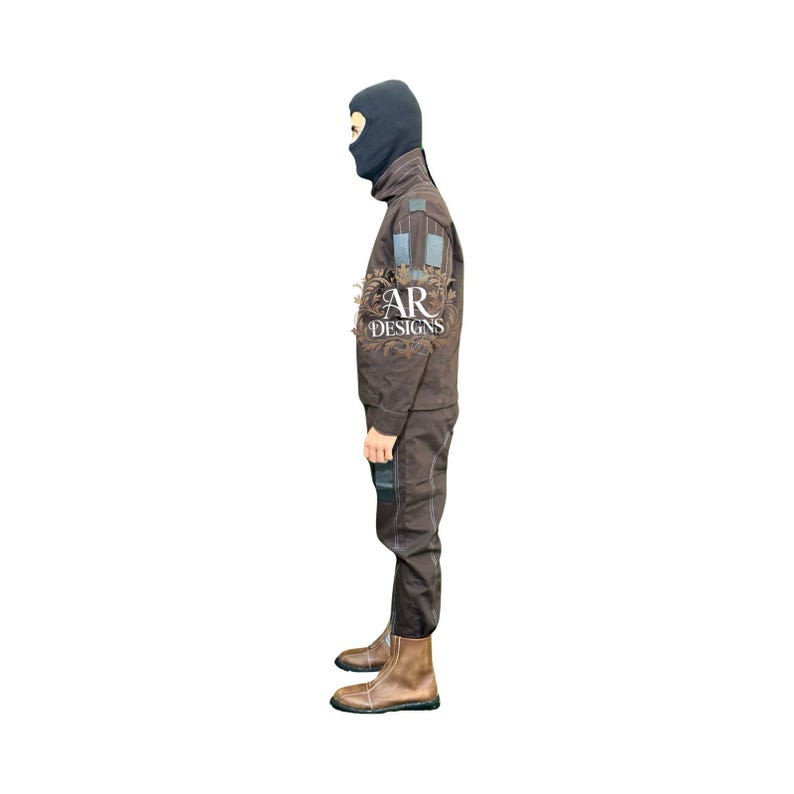 May include: A brown jumpsuit with a black balaclava. The outfit features blue and grey fabric patches on the sleeves and legs. The boots are brown leather. The logo "AR DESIGNS" is visible on the sleeve.