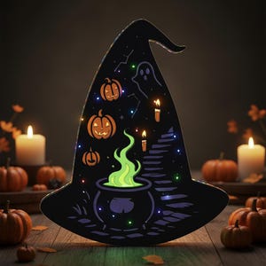 May include: A black witch hat-shaped Halloween decoration with illuminated pumpkins, a ghost, candles, and a bubbling cauldron. The hat is decorated with small lights and sits on a wooden surface, surrounded by pumpkins and candles.