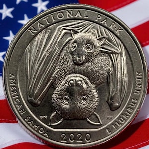 以下が含まれることがあります： 2 匹のコウモリが描かれた銀貨で、「NATIONAL PARK」と「AMERICAN SAMOA 2020」の文字が刻まれています。コインは、赤と白のストライプと星の青いフィールドを持つアメリカ国旗を背景にしています。