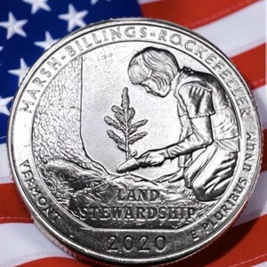 以下が含まれることがあります： 木を植えている人物が描かれた銀色の25セント硬貨。テキスト「LAND STEWARDSHIP」と「2020」が記されています。硬貨はアメリカ国旗を背景に配置されています。