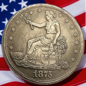May include: A detailed close-up of an antique coin with a seated figure holding a branch, surrounded by stars. The coin, dated 1875, features the inscription "IN GOD WE TRUST" and the word "LIBERTY". The coin rests on a backdrop of the American flag.