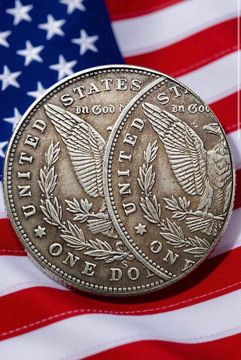 May include: Two silver dollar coins with detailed engravings of an eagle and the words "United States of America" and "One Dollar." The coins are set against a backdrop of the American flag, with its red and white stripes and blue field of stars.