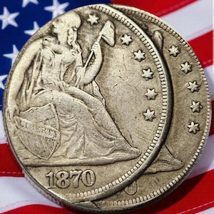 May include: Two antique silver coins, dated 1870, with a seated Liberty design, set against an American flag. The coins show detailed imagery, including stars and the word "LIBERTY" on a shield. The coins are a historical collectible.