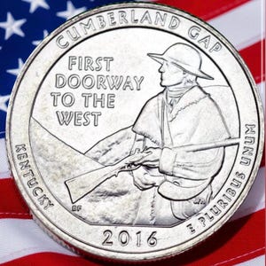 May include: A silver 2016 Kentucky quarter featuring a frontiersman with a rifle, the text "First Doorway to the West," and "Cumberland Gap." The coin is set against a backdrop of the American flag.