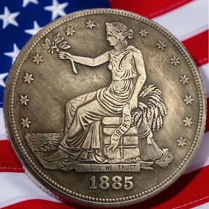 May include: A detailed close-up of an antique coin featuring a seated woman holding a branch, with the word "LIBERTY" visible. The coin is dated 1885 and set against a backdrop of the American flag.
