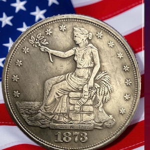 May include: A silver coin with a seated Liberty design, holding a branch and wheat. The coin is dated 1873 and features the inscription "In God We Trust." The background includes the American flag.