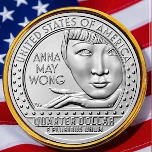 May include: A silver quarter dollar coin featuring Anna May Wong, with the text "United States of America" and "Quarter Dollar". The coin is set against a backdrop of the American flag.