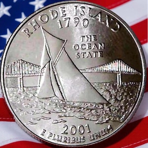 Può includere: Una moneta da un quarto di dollaro del Rhode Island in argento con un disegno di barca a vela, le parole "Rhode Island 1790" e "The Ocean State". La moneta è posta su uno sfondo della bandiera americana.
