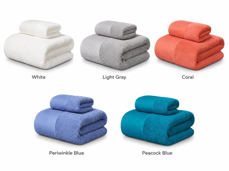 May include: Five sets of folded towels, each consisting of one large bath towel and one smaller hand towel. The sets are available in five distinct solid colors: white, light gray, coral, periwinkle blue, and peacock blue, all featuring a textured border.