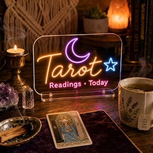 May include: A rectangular acrylic neon sign featuring the purple crescent moon, a blue star, and the orange text "Tarot" above the pink text "Readings • Today". The sign is mounted on a clear acrylic base and displays vibrant glowing light.