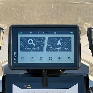 Könnte beinhalten: Ein Garmin GPS-Gerät mit schwarzem Rahmen zeigt eine Kartenoberfläche mit dem Text "Kam viesť?" und "Zobraziť mapu". Der Bildschirm zeigt Symbole für Navigation, Musik und Einstellungen. Die Uhrzeit wird als 17:27 angezeigt.
