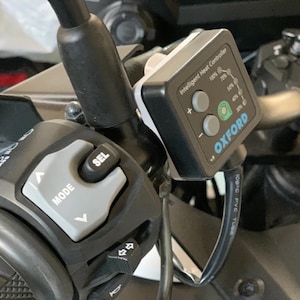 Op de afbeelding: Detail van het motorstuur met een zwart en grijs bedieningspaneel en een "OXFORD" Intelligent Heat Controller. De controller geeft warmteniveaus weer en heeft knoppen. Een zwarte kabel is aangesloten op de controller.