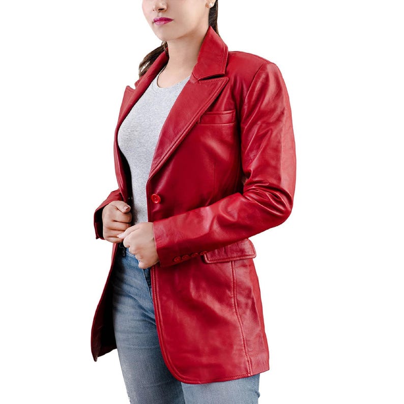 May include: A vibrant red leather blazer with a classic notched lapel and a single-button closure. The blazer features a tailored fit, a chest pocket, and two front pockets. The sleeves are long, and the blazer is worn over a gray t-shirt and blue jeans.