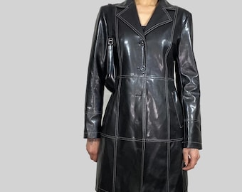 May include: Black leather coat with white stitching details. The coat features a classic collar, button closure, and a tailored fit. The long coat is a stylish outerwear piece.