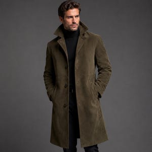 Puede incluir: Una gabardina de color verde oliva con cuello ancho, mangas largas y tres botones oscuros en la parte delantera. El abrigo se lleva sobre un suéter de cuello alto negro, creando un aspecto superpuesto con una silueta estructurada y textura lisa.