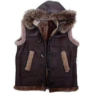 Op de afbeelding: Een bruin leren vest met een met bont gevoerde capuchon en binnenkant. Het vest heeft knevelsluitingen en bontafwerking langs de randen en zakken. Dit bovenkledingstuk is ontworpen voor warmte en stijl.