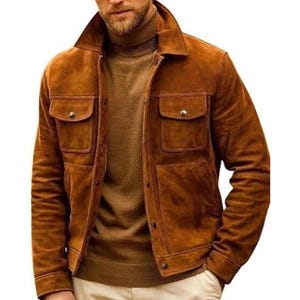 Puede incluir: Chaqueta de ante marrón con dos bolsillos en el pecho y dos bolsillos inferiores. La chaqueta tiene cierre de botones y cuello. El modelo lleva un jersey de cuello alto marrón. La chaqueta es de un tono cálido y terroso.