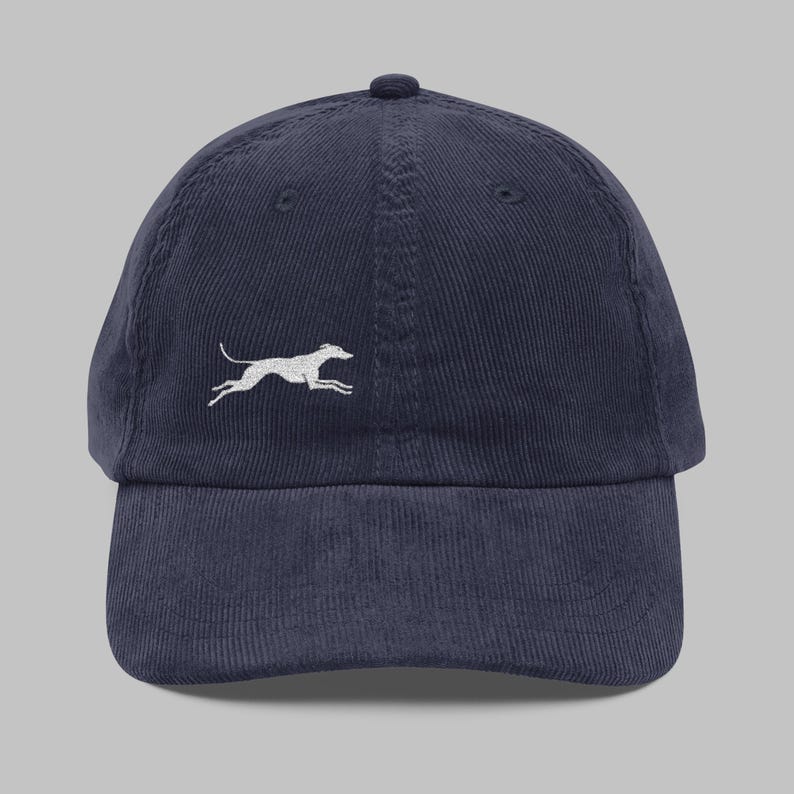 a navy corduroy dad hat with a small white silhouette of a running greyhound or whippet on the front